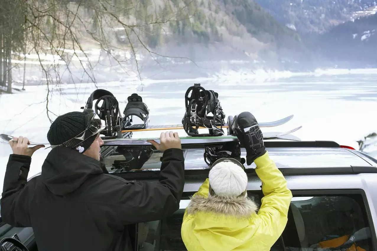 Top Tips for Traveling with Your Ski and Snowboard Equipment couple taking snowboards of roof rack 2025 04 04 09 46 53 utc