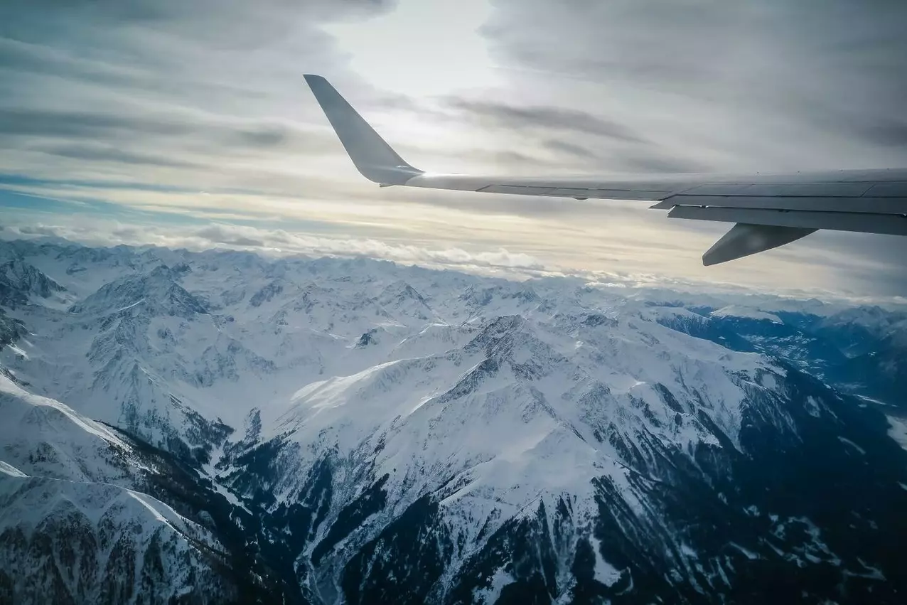 Top Tips for Traveling with Your Ski and Snowboard Equipment flying over snowy white mountain top view from a 2025 01 10 00 17 16 utc